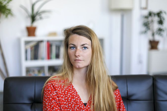 Portrait of serious young woman sitting on sofa