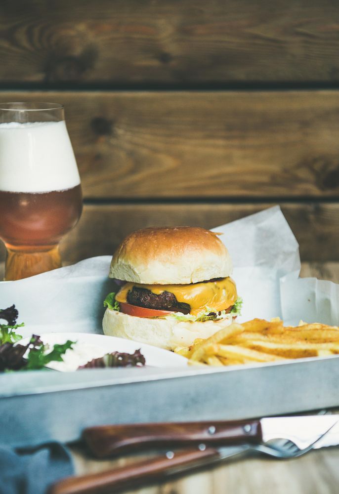 Classic hamburger with fries and beer at wooden restaurant table