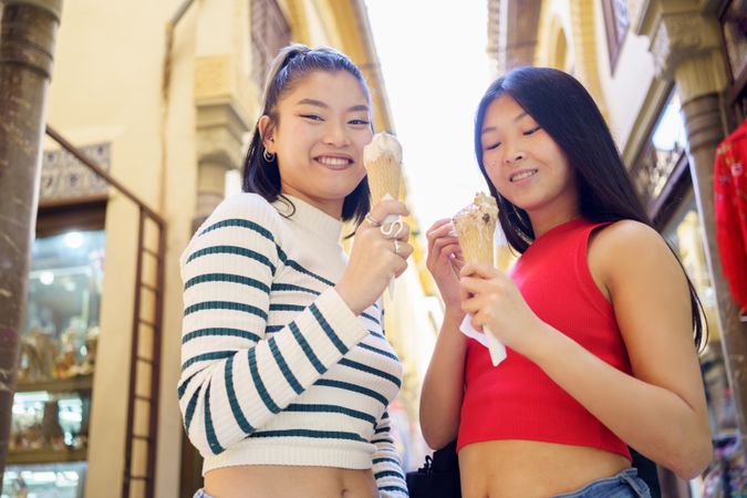 Two young Chinese women eating an ice cream cone in the typical streets of Granada