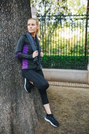 Woman resting on tree trunk after jogging