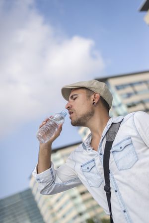 Male with city in background sipping water