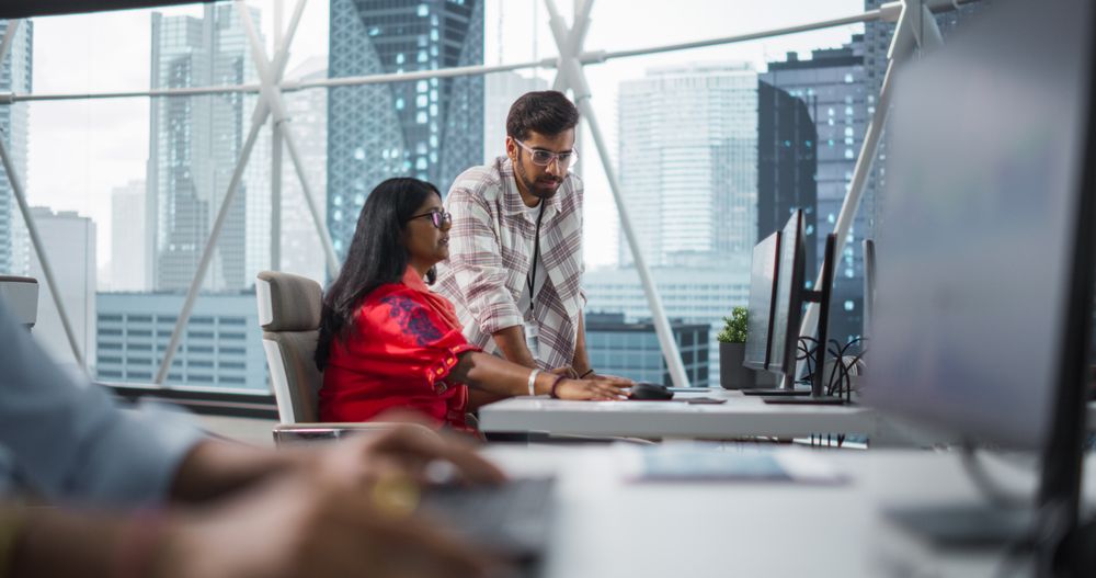 South Asians Colleagues Using Desktop Computer, Comparing Reports and Data in a Modern Office
