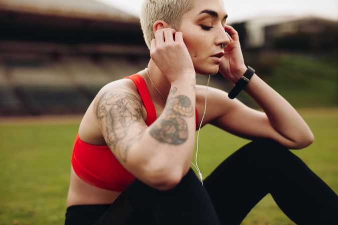Close up of a woman athlete sitting on ground listening to music wearing earphones