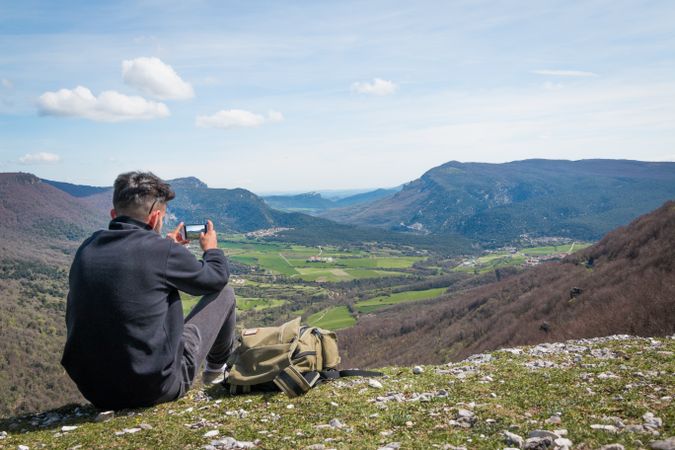 Man taking picture of valley with smartphone