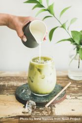 Iced matcha drink with hand pouring cream from pitcher 4AjNWb