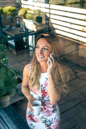 Smiling woman talking on the cellphone with coffee cup