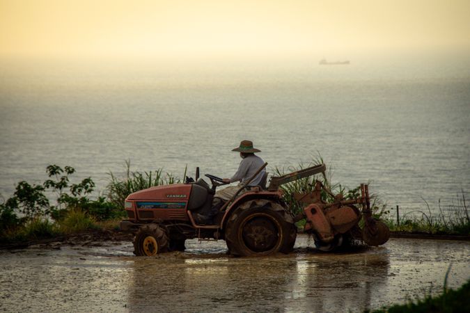Side view of farmer riding a tractor on water