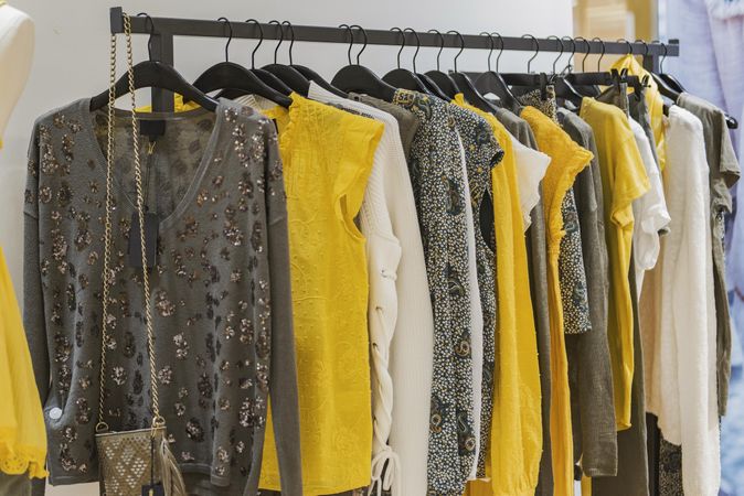 Clothes rack of yellow and gray women's shirts in fashion store