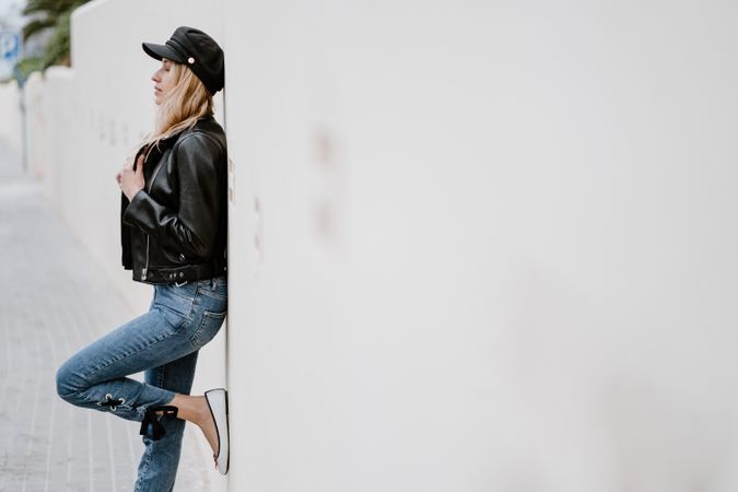 Stylish woman confidently leaning on white wall