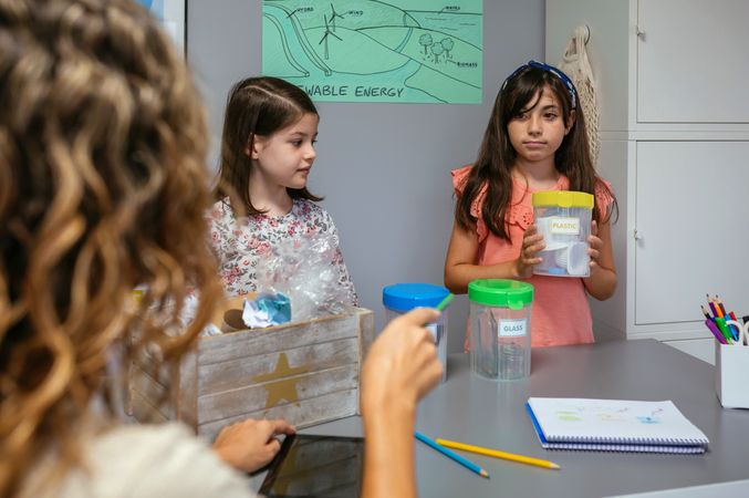 Student looking at teacher while holding sorting waste bin