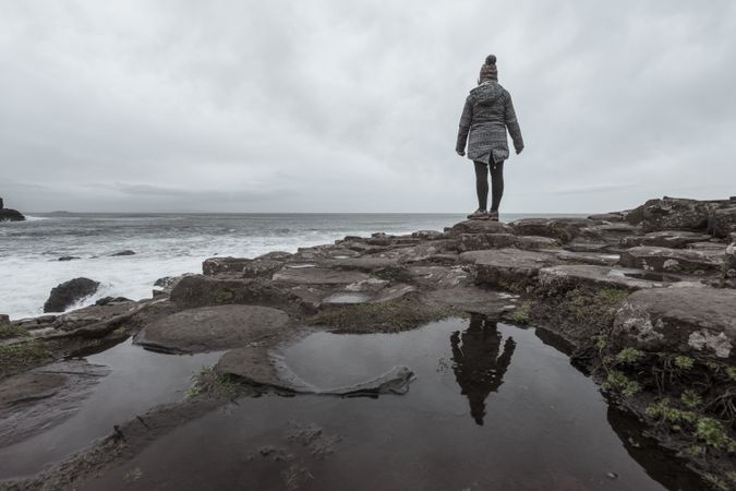 Female standing on cliff and contemplating