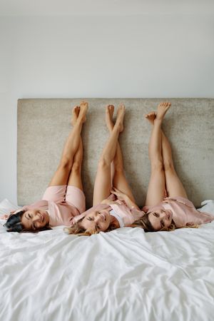 Young females lying on the bed with legs up and smiling