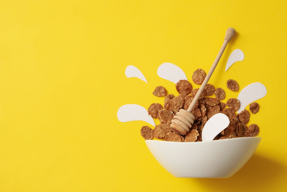 Bowl with muesli and dipper on yellow background