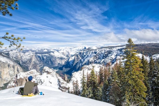 Anonymous explorer sitting on snowy mountain slope in Yosemite California in winter