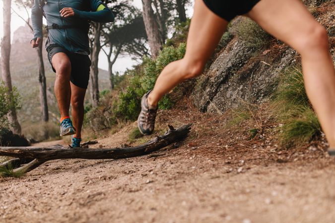 Legs of healthy couple running on mountain trail in morning
