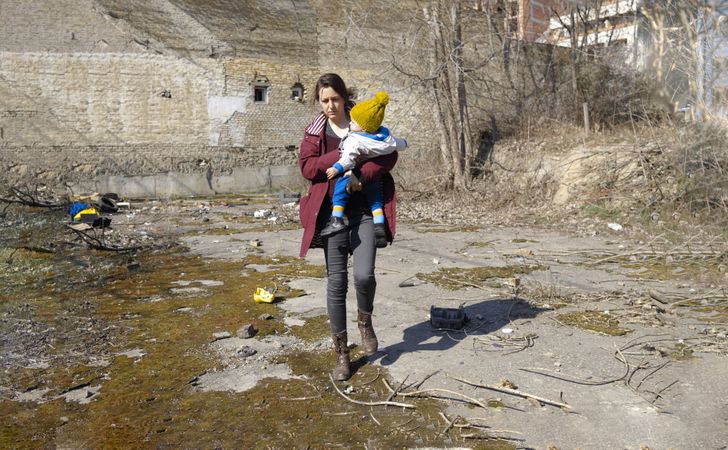 Mother holding child walking through rubble
