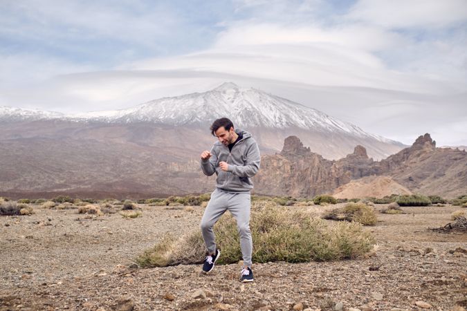 Male traveler standing on hillside area and boxing