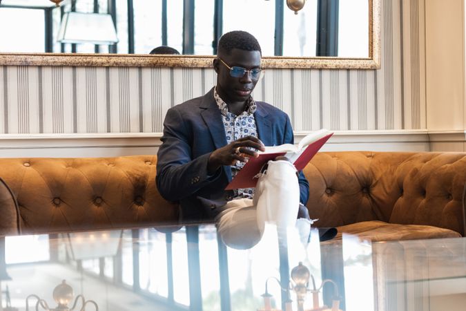 Pensive Black businessman reading book in cafe