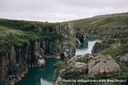 Woman standing on edge of cliffs over water 5lXnm5