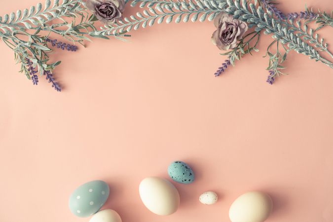 Creative layout made with spring flowers leaves and Easter eggs on pastel pink background