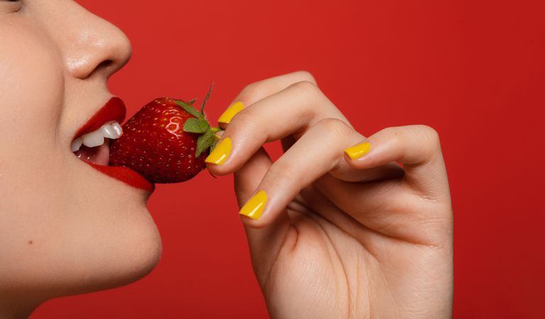 Close up of woman holding strawberry at her mouth