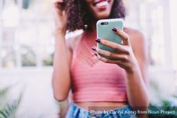 Young woman smiling while texting on a smartphone DbGxV0