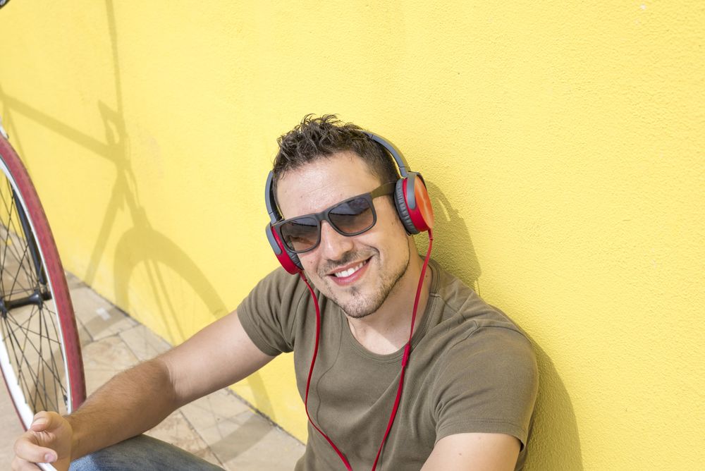 Looking down at happy man with red headphones sitting outside