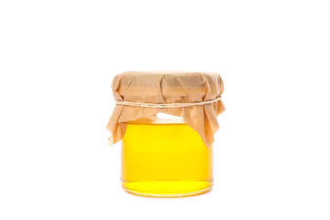 Glass jar with honey isolated on blank background