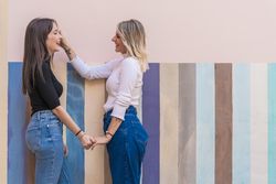 Happy girlfriends standing against painted urban wall