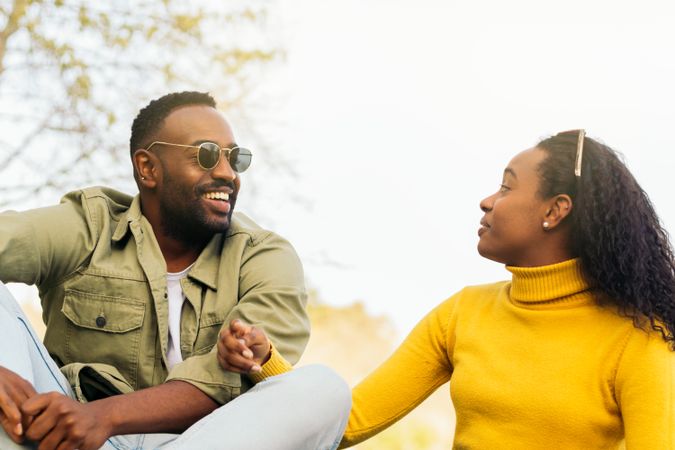 Cute Black couple talking sitting in a park