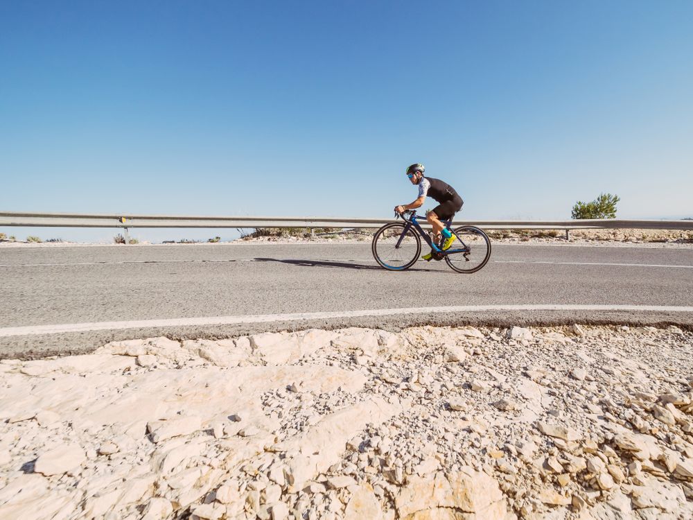 healthy man riding a bicycle on a mountain road in a sunny day