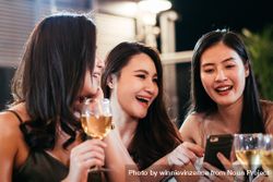 Group of woman watching video on mobile phone in bar 0Lddeg