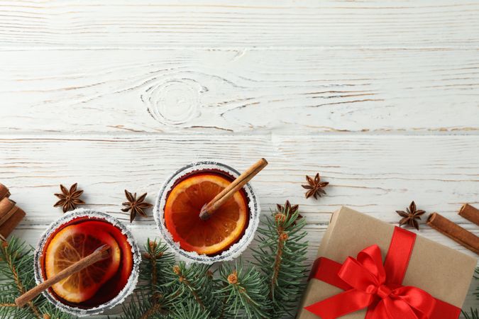 Glasses of tasty mulled and gift on wooden background, top view