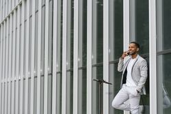 Elegant Black man talking smartphone leaning building