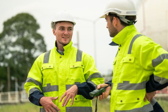 Engineer worker in protective uniform talking with colleagues at construction site