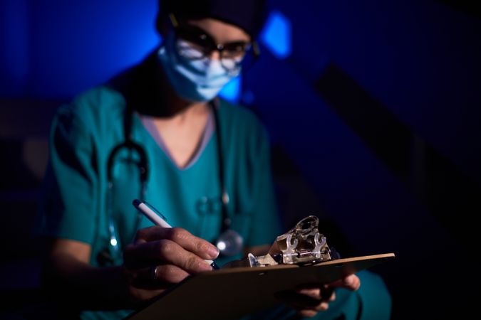 Focused female doctor writing medical report in darkness