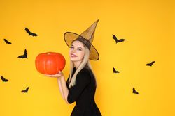 Concept of Halloween, young woman on yellow background