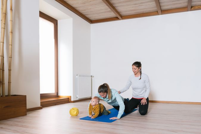 Fitness instructor helping mother with push ups