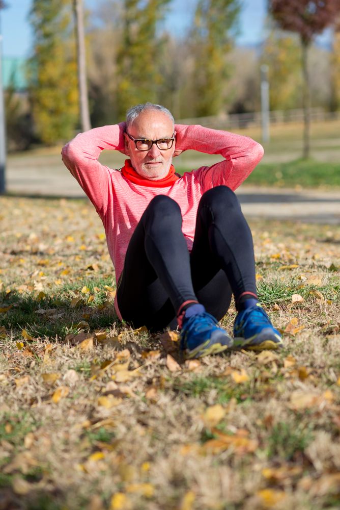 Older male doing sit ups in park