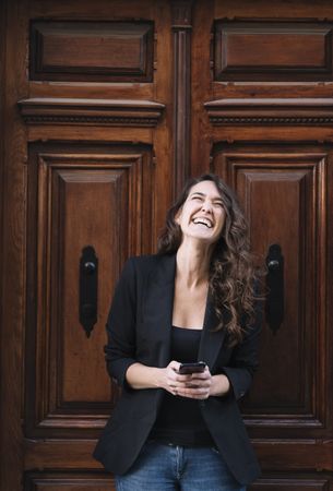 Young female using mobile phone on wooden door