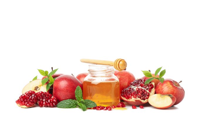 Fall fruit of pomegranates and apples, pot of honey centered on table