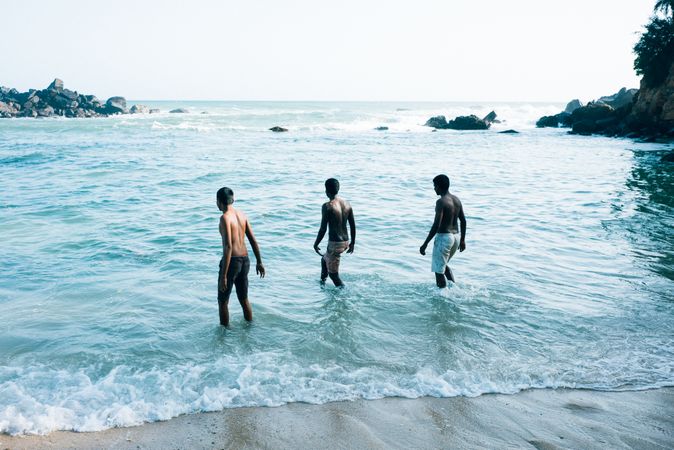 Three men wading into the waters of Sri Lanka
