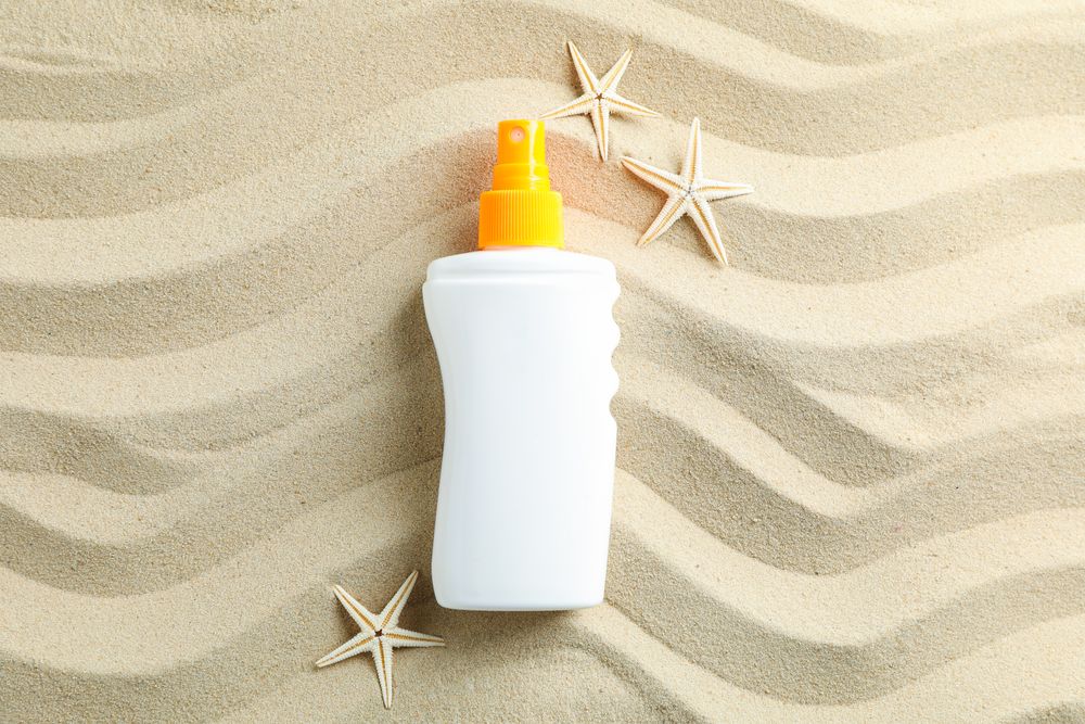 Clear sea sand with sunscreen and starfishes, space for text. Summer vacation background