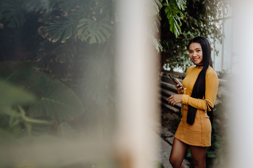 Charming long haired Asian woman browsing smartphone in botanical garden