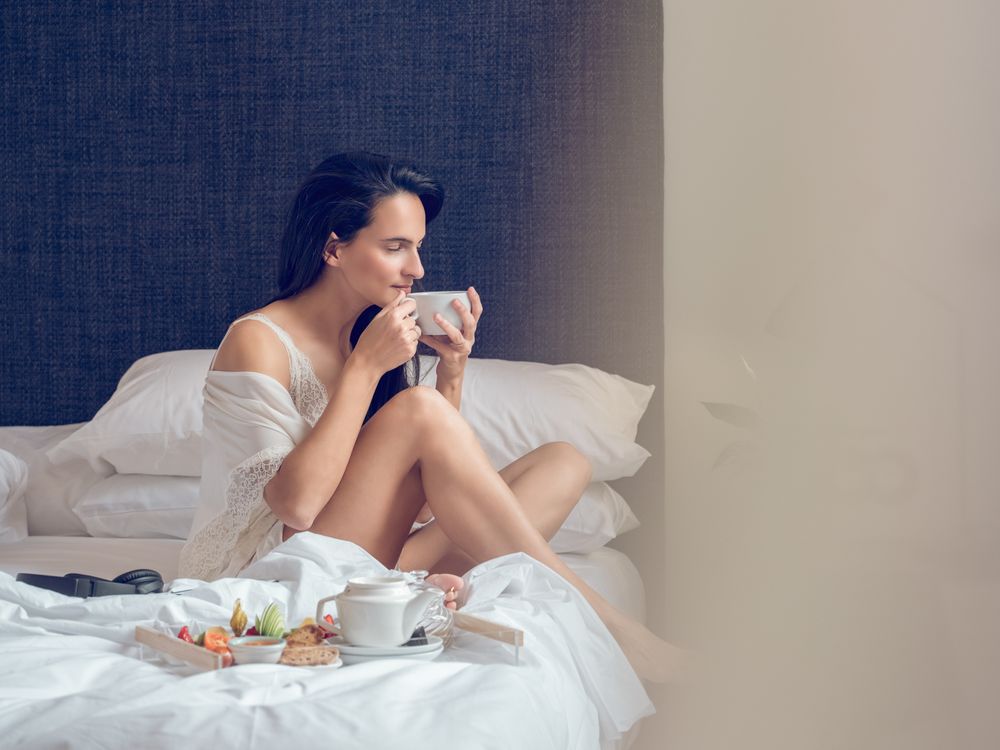 Content woman having breakfast on bed
