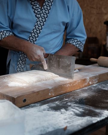 Chef cutting a dough on wooden cutting board