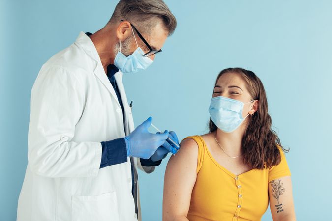Male doctor giving vaccination to a woman