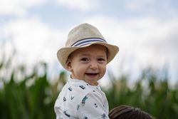Stylish kid in hat smiling and looking at camera in field