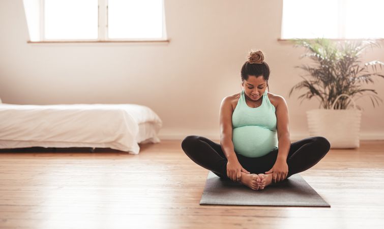 Portrait of young pregnant female working out at home