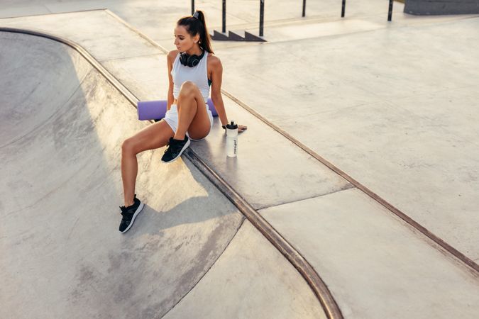 Fit woman relaxing after workout training sitting in skate park